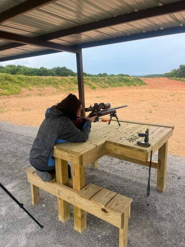 Shooter using a benchrest rifle setup under covered firing line at Recon By Fire range