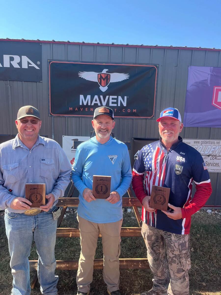Winners holding plaques in front of sponsor banners after a shooting match at Recon By Fire