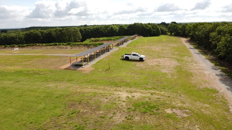Drone view of covered rifle shooting bays and surrounding open field at Recon By Fire Precision Range in Oklahoma