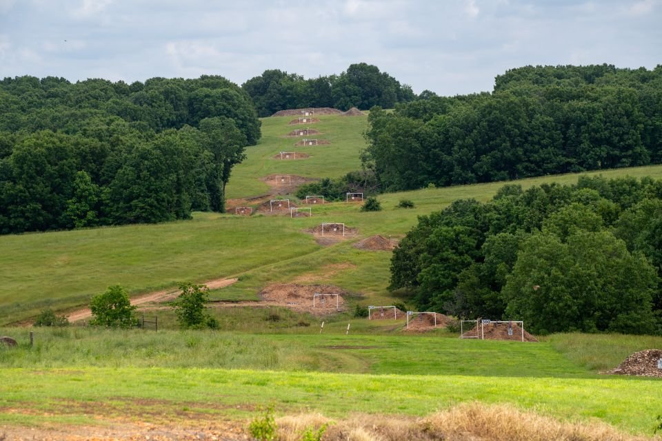 Distant view of multiple target berms set up for long-range shooting at Recon By Fire Range in Oklahoma, surrounded by forested hills