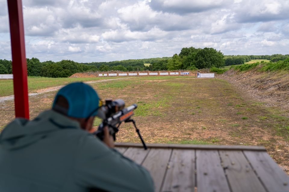Shooter aiming downrange to sight in rifle at Recon By Fire Precision Range in open Oklahoma landscape