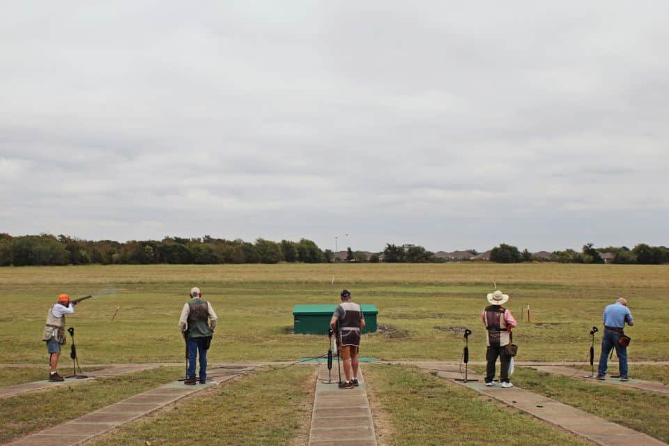 Group of shooters lined up at outdoor trap shooting field at Recon By Fire Precision Range in Oklahoma